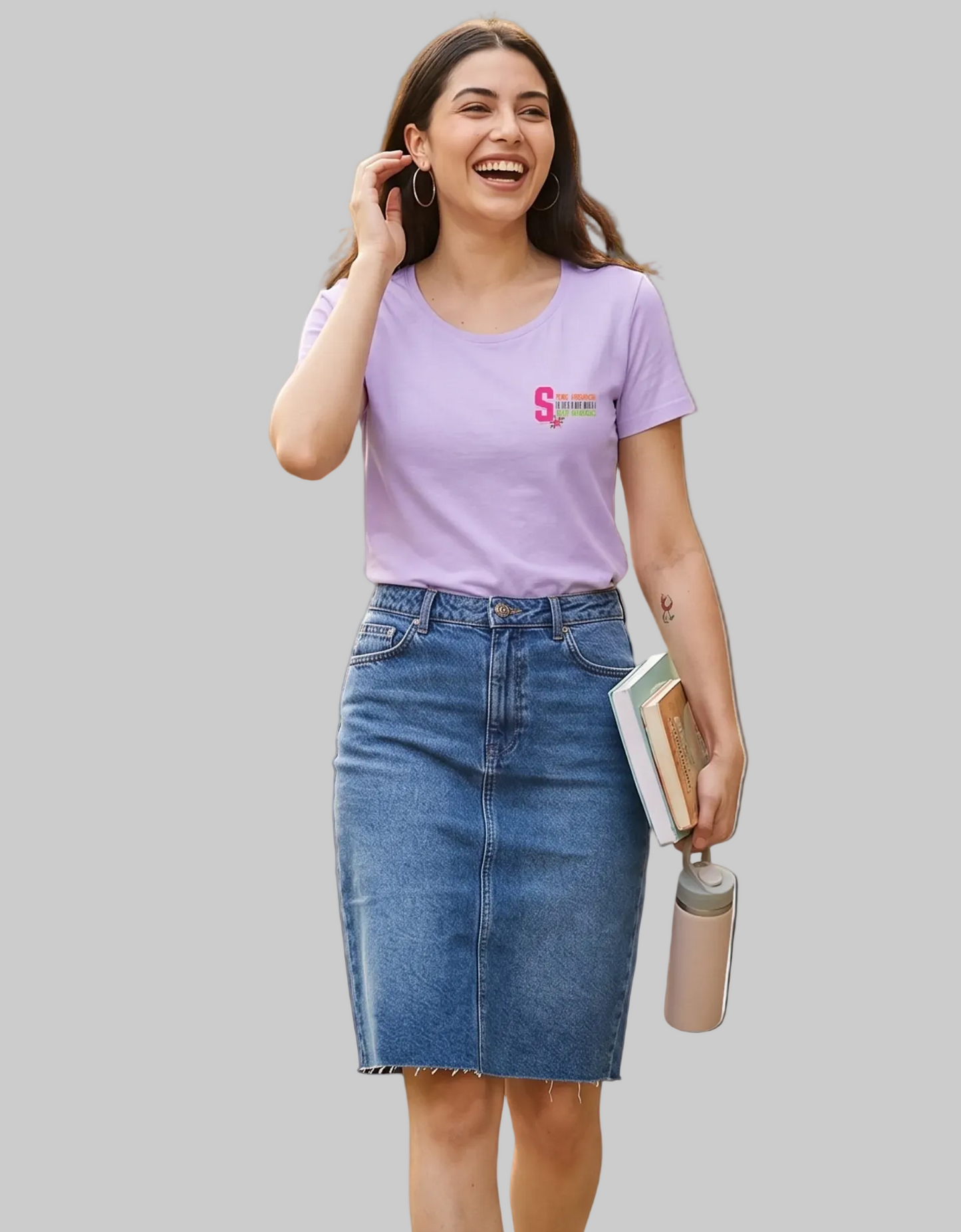 Woman wearing a purple t-shirt with anime style logo on front and blue denim skirt, holding a phone and a water bottle on a white background